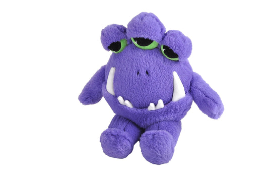 An image of a purple plushie against a white background. The plushie has three half-opened green eyes at the top of his head, and long white fangs sticking out of his closed mouth. Short arms and legs are attached at his side and bottom