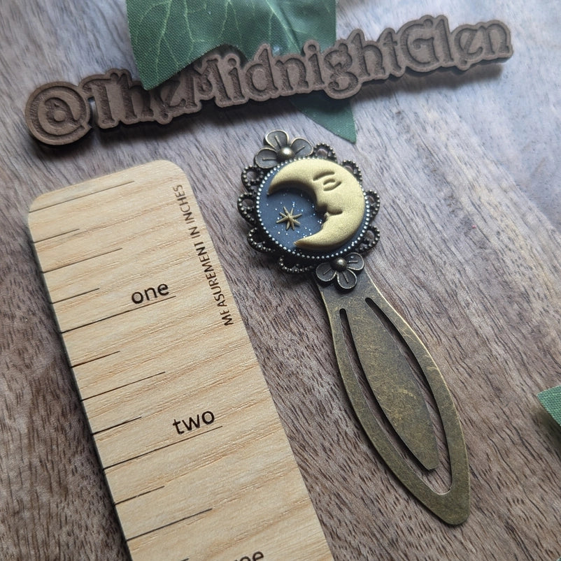 Decorative bookmark with moon design on a wooden ruler and textured surface