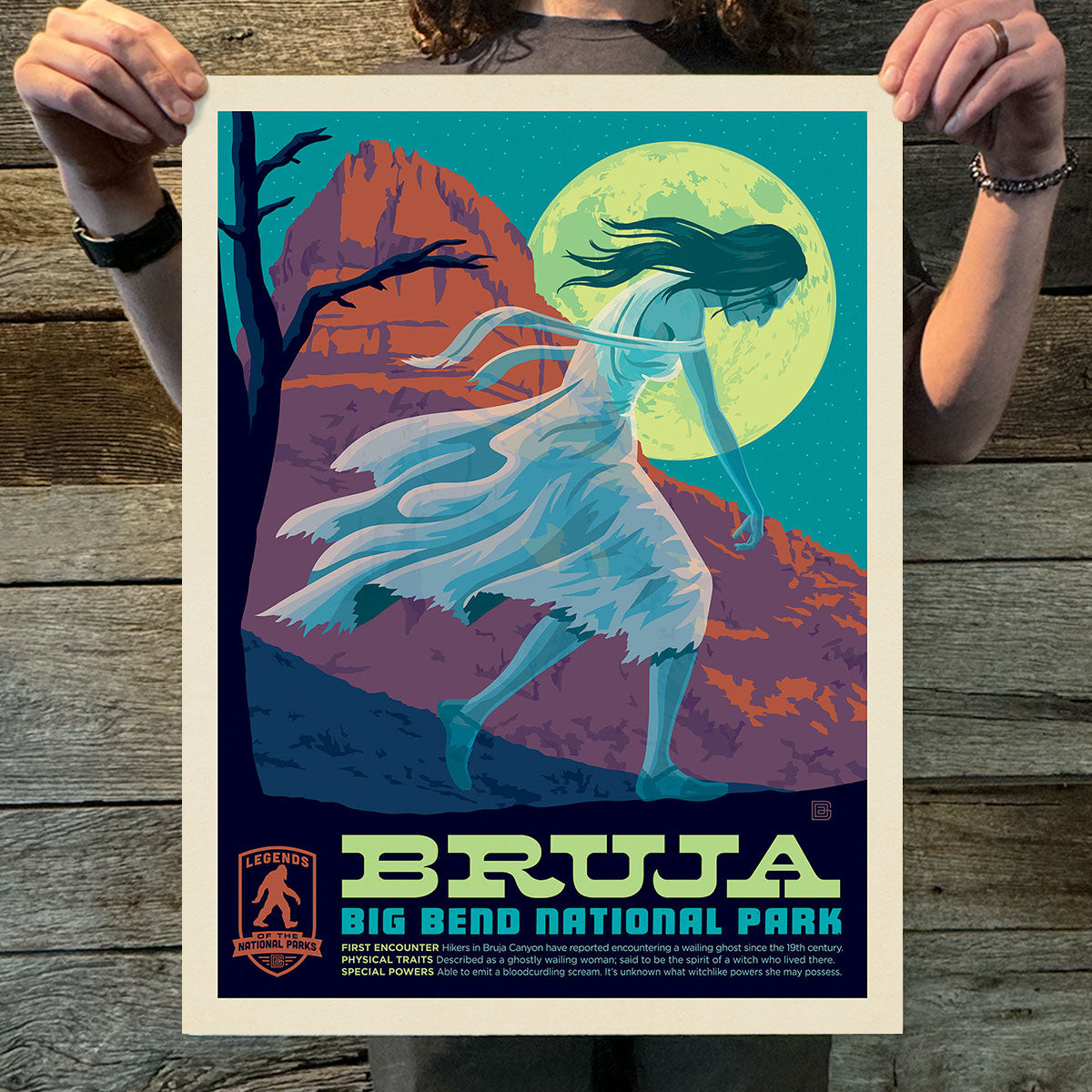 Person holding a 'Bruja' Big Bend National Park poster with a stylized woman and mountain landscape.