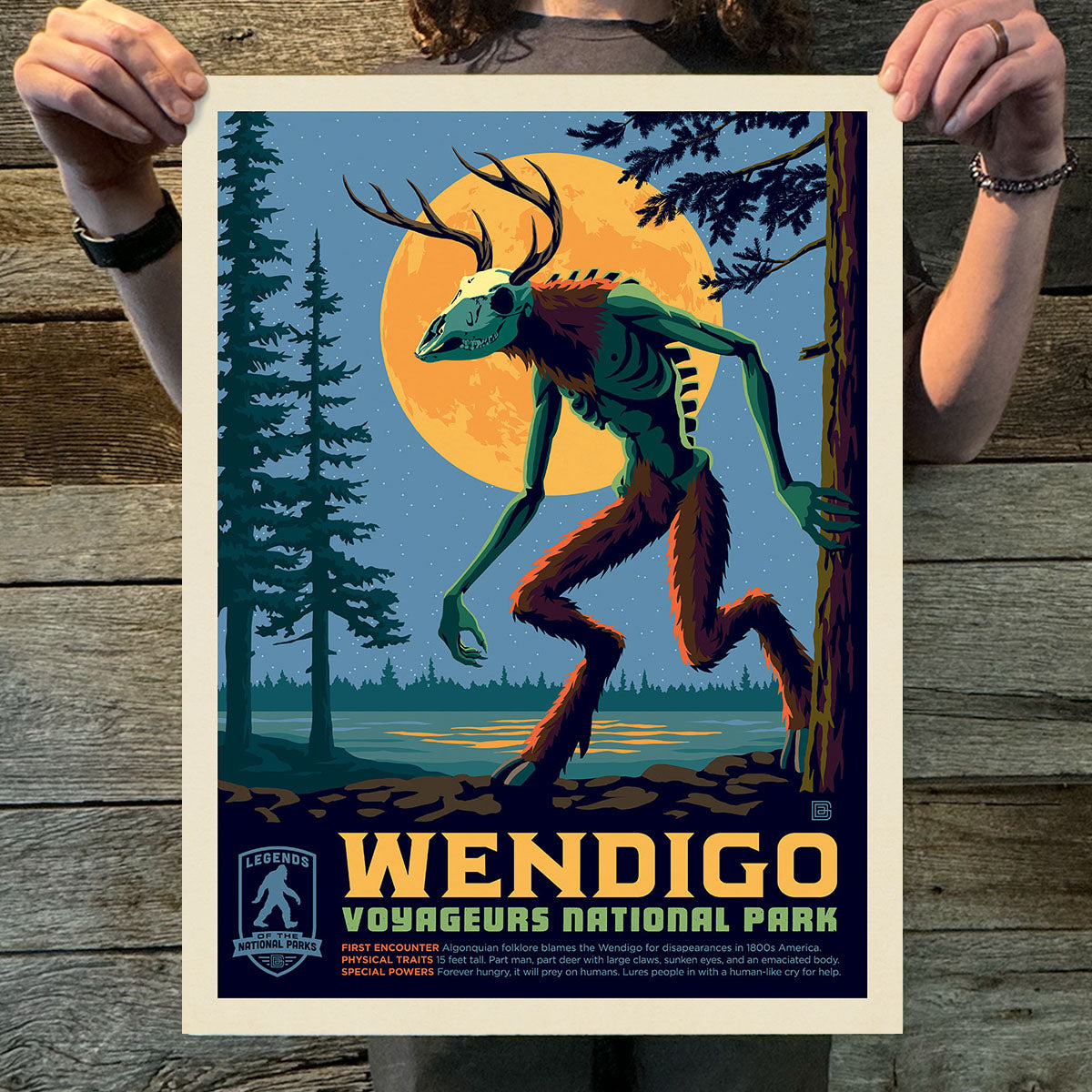 Poster of a wendigo creature in Voyageurs National Park held by a person on a wooden surface.