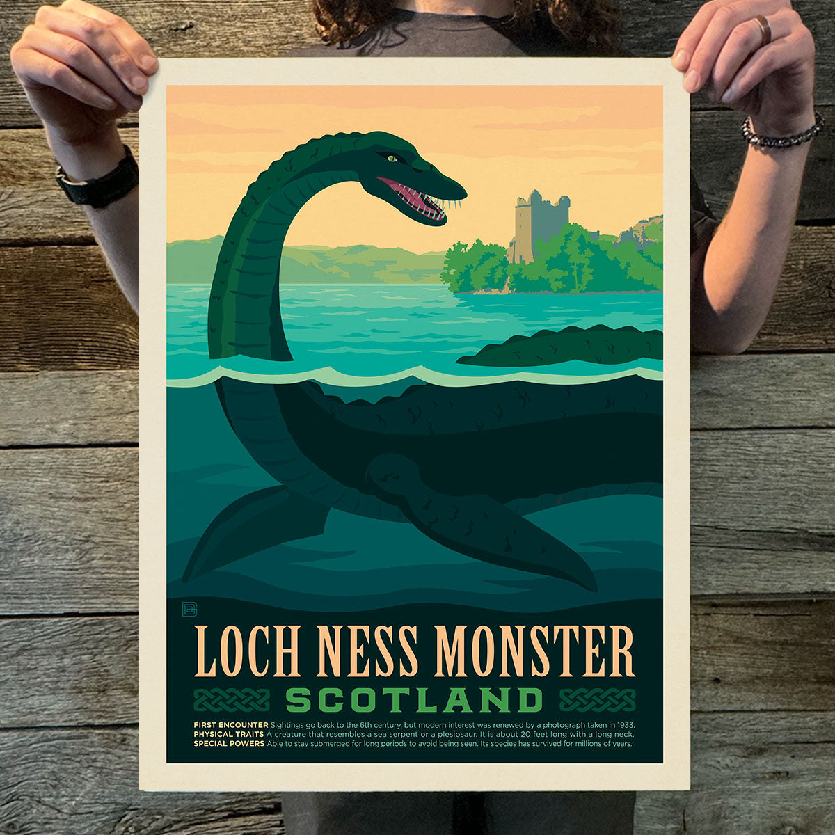 Poster of Loch Ness Monster with scenic background held by a person on wooden surface