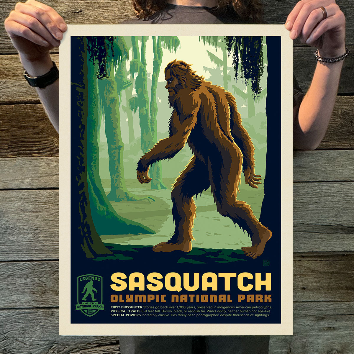 Poster of a Sasquatch in a forest with 'Sasquatch Olympic National Park' text on a wooden surface.