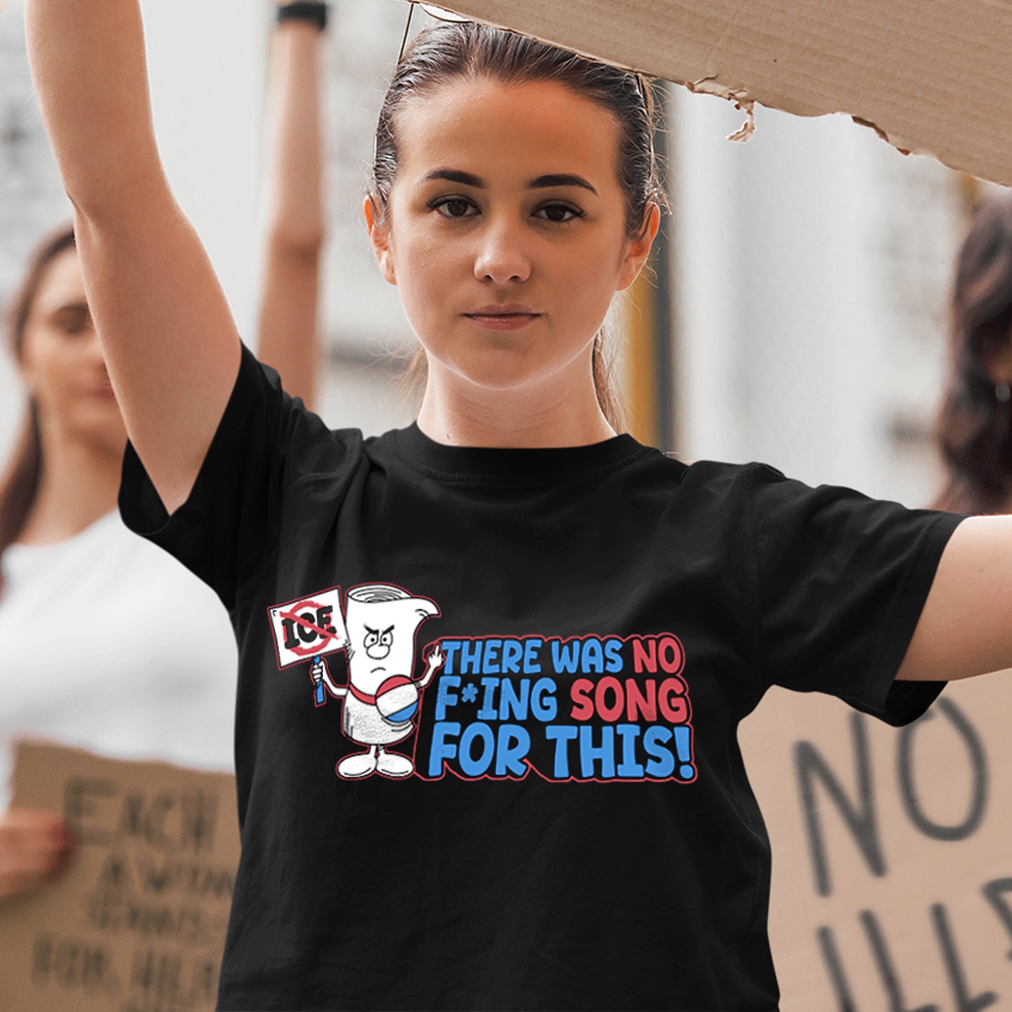 A model in a black tee shirt, participating in a protest. On the front of the shirt is a scroll holding a protest sign and giving the middle finger. Red and blue text says there was no F-ing song for this