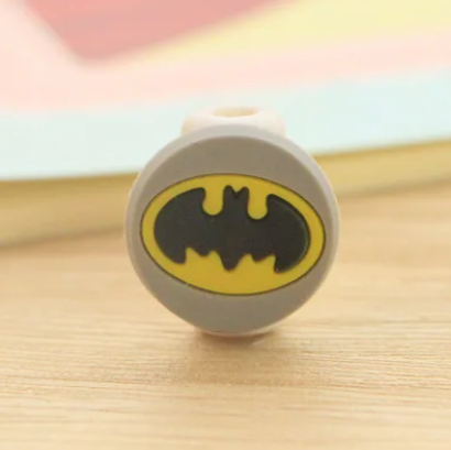 Close up view of a plastic phone charger clip, with the Batman logo on the front.