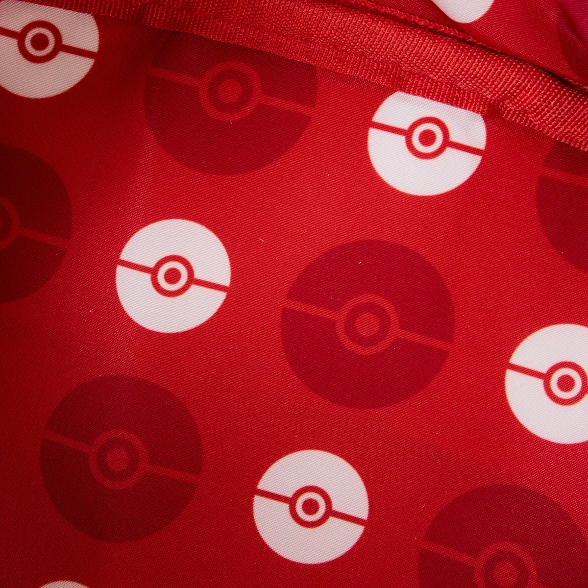 A red swatch of fabric with red and white Pokemon balls printed across it in a repeating pattern.