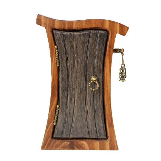 A miniature, curvy wooden door and frame, against a white background. The door is a dark gray color, with brass hinges and a round doorknob on the sides. Sticking out from the frame is a tiny brass post, with a miniature lantern hanging from it.