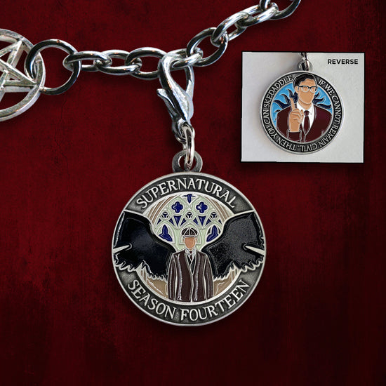 Close up image of a charm on a silver bracelet chain. The charm depicts depicts a man in a black suit with black angel wings. Around the edge is raised text saying Supernatural Season Fourteen. At the top right is an inset image of the charm's other side, showing a man in a brown sweater and tie wearing glasses, holding a finger up admonishingly. Behind him is a blue background with black sun beams. Around the edge is raised text saying "If we cannot remain civil, then you can skedaddle