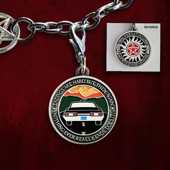 Front and back views of an enamel charm on a silver chain. On the front is the anti-possession symbol in silver and red. Around the edge of the coin, raised text says "Supernatural, Fifteen Seasons. Then... Now..." The back of the charm depicts the back of a black 1967 Chevy Impala driving on a black road toward a sunset. Around the edge is raised text saying “Endings are hard, but then again nothing ever really ends, does it?" Behind the charms is a swirling red background.