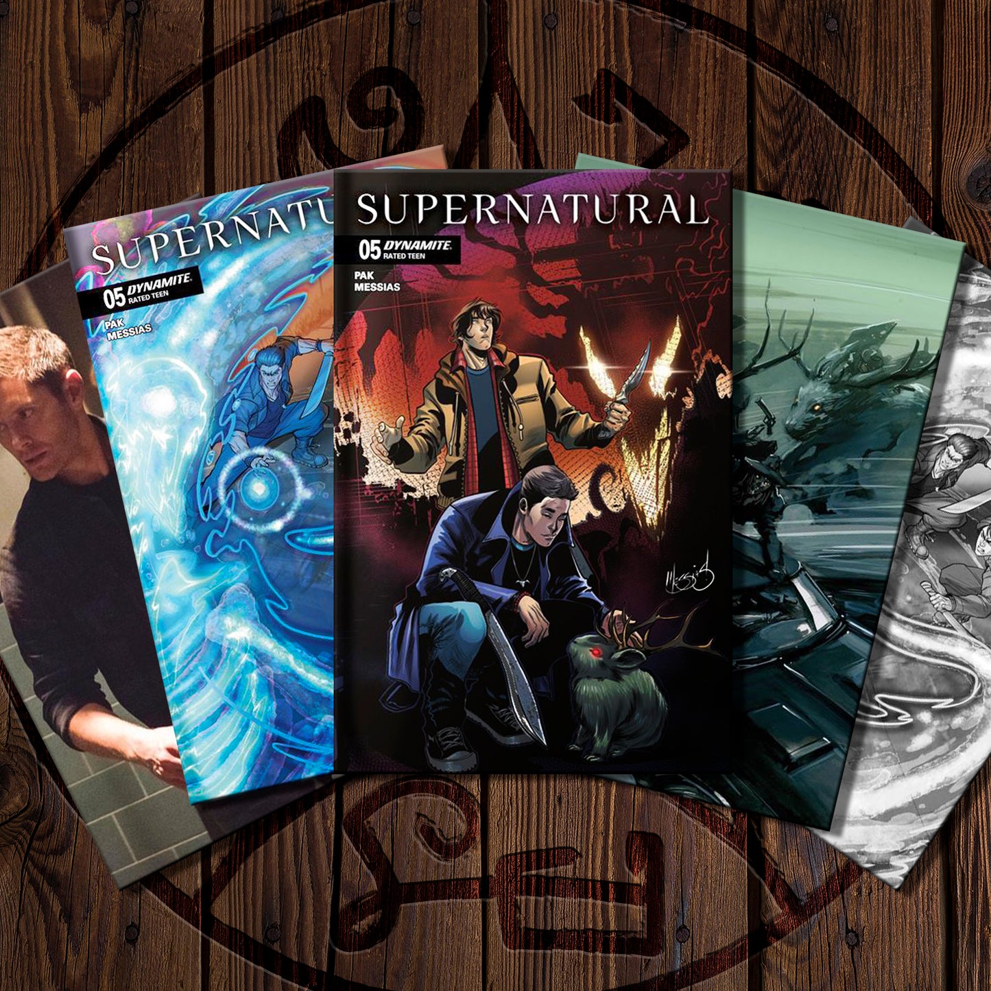 Four 'Supernatural' comic books on a wooden surface with the show's logo.