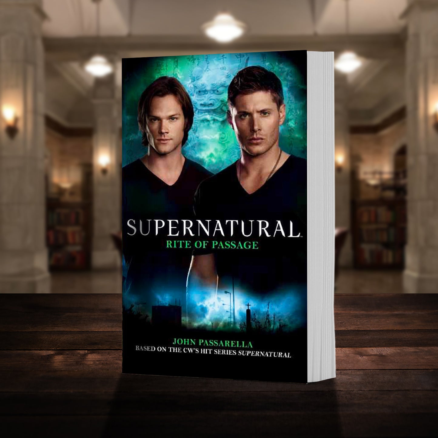 A copy of the book "Supernatural: Rite of Passage" pictured in the "bunker" from Supernatural. The cover shows early-season Sam and Dean Winchester and reads "Supernatural Rite of Passage - Based on the hit CW series SUPERNATURAL by John Passarella”