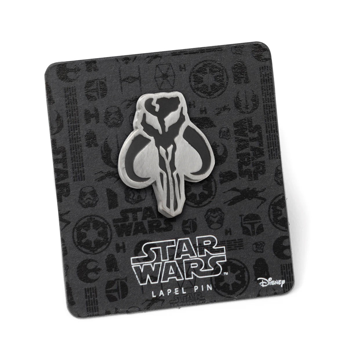 A silver and black Mandalorian-themed lapel pin on a black cardboard backing