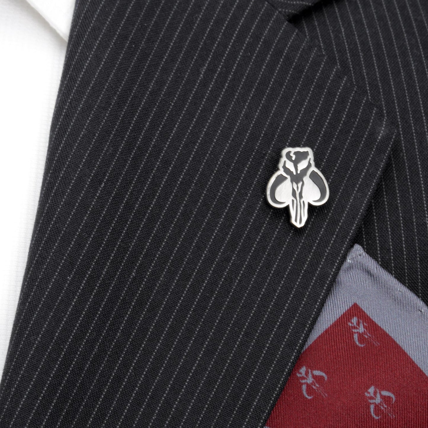 A silver and black Mandalorian-themed lapel pin on a black suit jacket
