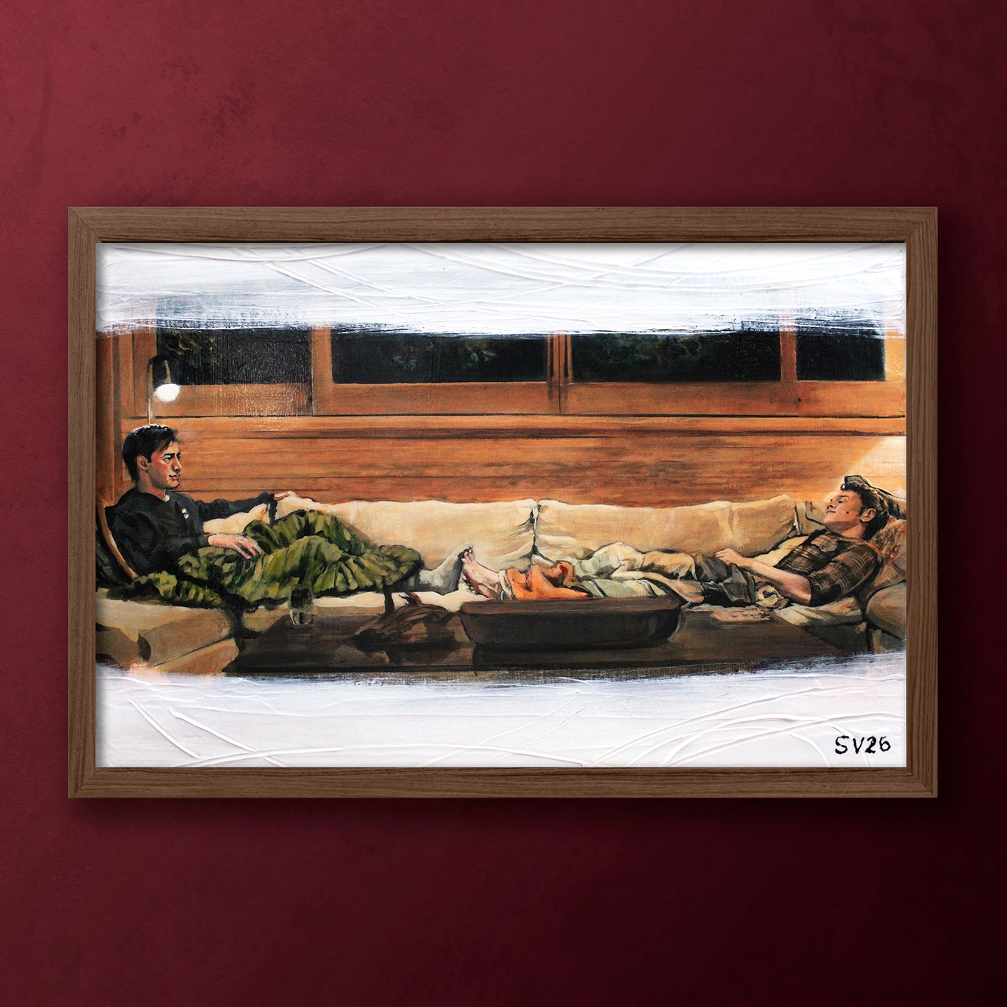 Framed artwork of two people sitting on a couch in a cottage.