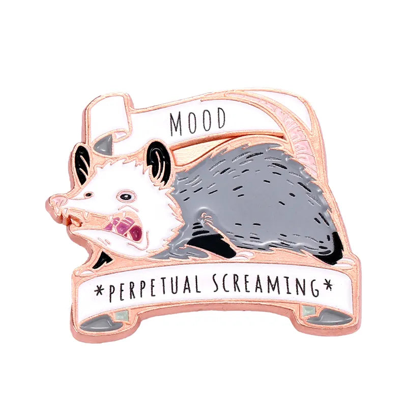 Close up view of an enamel pin on a white background. The pin depicts a cartoonish opossum, mouth wide open in a scream. Above and below the opossum are white ribbons with black text saying "Mood: perpetual screaming."