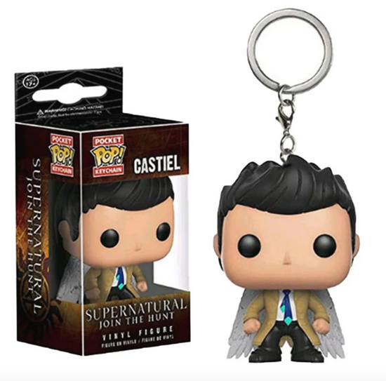 Close up of a keychain in the shape of the angel Castiel, wearing black pants and a tan raincoat. His white wings are visible behind him. His features are cartoonish, with an extra large head. Next to the keychain is a brown box containing the same keychain. At the bottom of the box is white text saying "Supernatural, Join the Hunt. Vinyl figure."