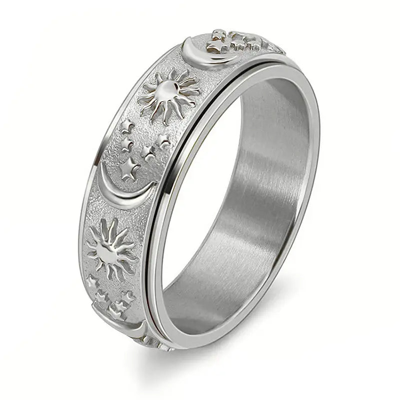 Close up view of a silver ring against a white background. Around the surface of the ring are raised depictions of the sun, the moon, and stars.