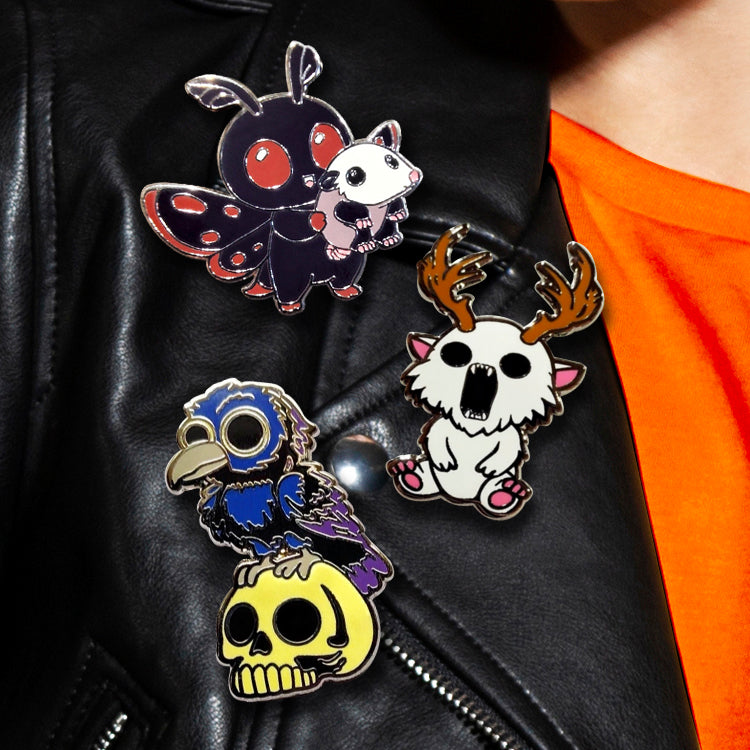 Three colorful pins on a black leather jacket with an orange shirt.
