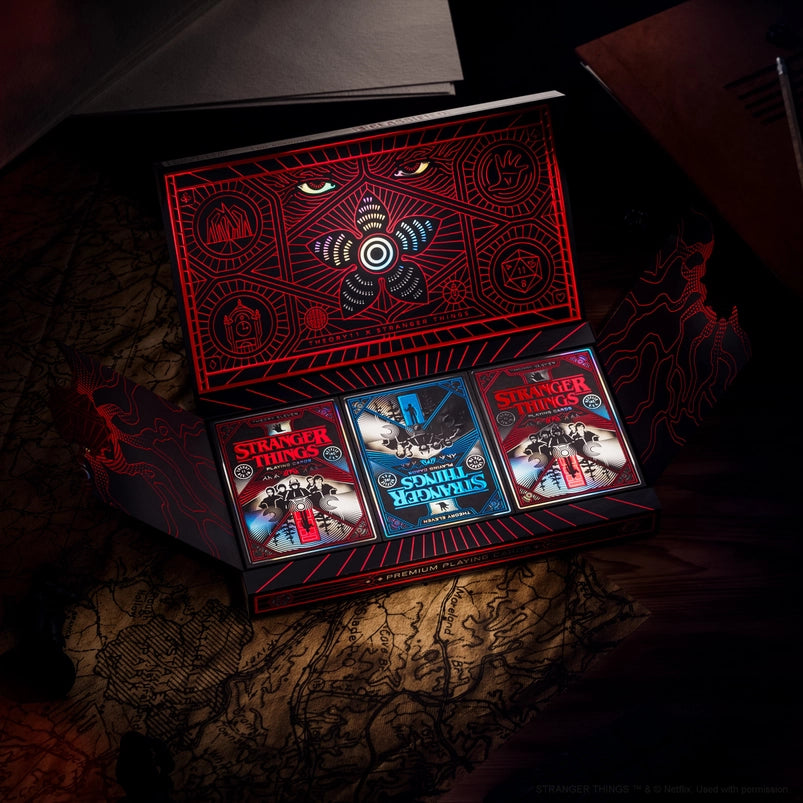 A red and black box holding three decks of playing cards, themed to the TV series Stranger Things.