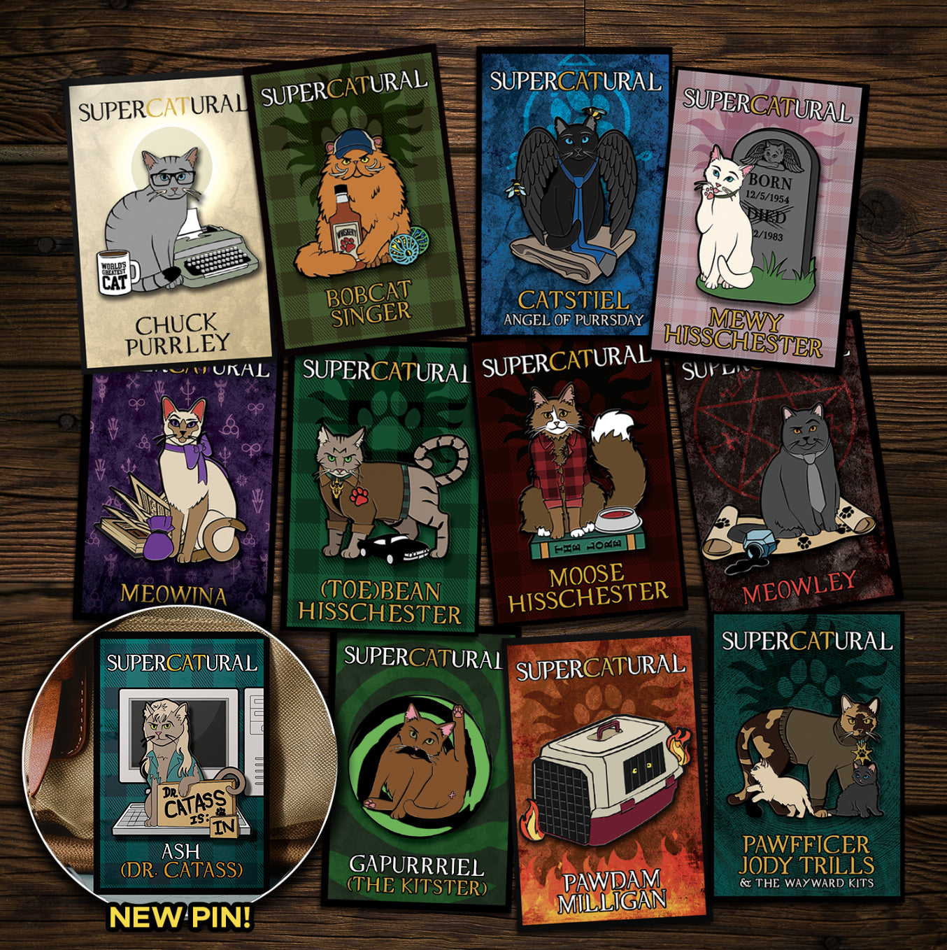A collection of enamel pins on a wooden table. Each pin depicts a character from the TV series "Supernatural" reimagined as cats. An inset in the bottom left corner reads "NEW PIN!" and has an image of Ash, the newest pin.