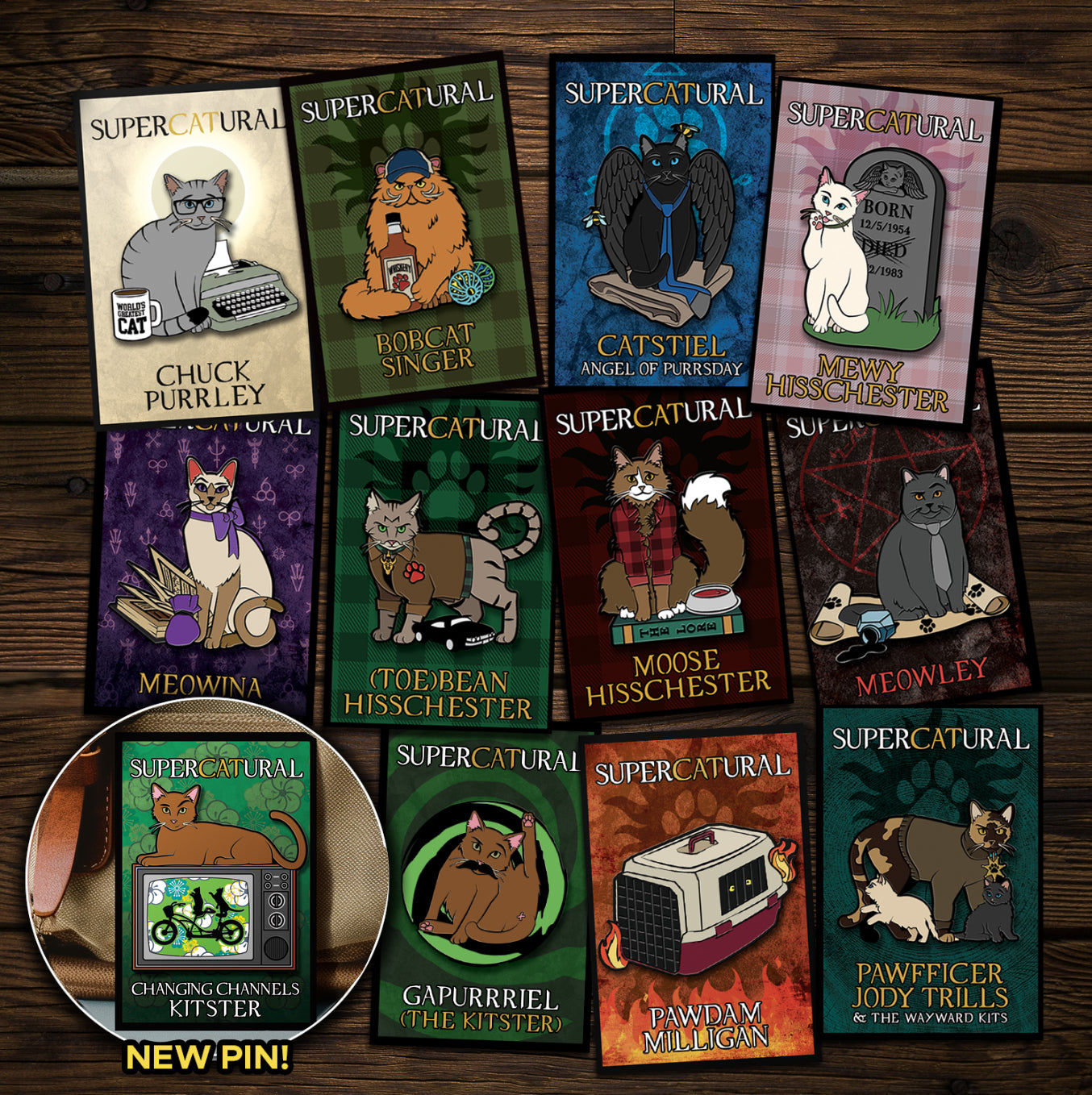 A collection of enamel pins on a wooden table. Each pin depicts a character from the TV series "Supernatural" reimagined as cats. An inset in the bottom left corner reads "NEW PIN!" and has an image of Changing Channels Kitster, the newest pin.