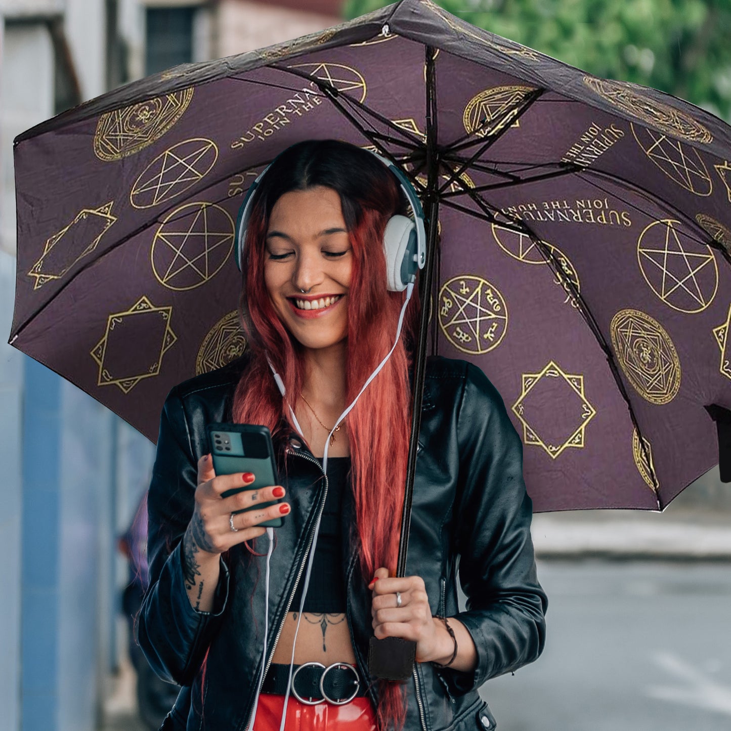 A female model carrying a purple umbrella covered in symbols from the TV series Supernatural.