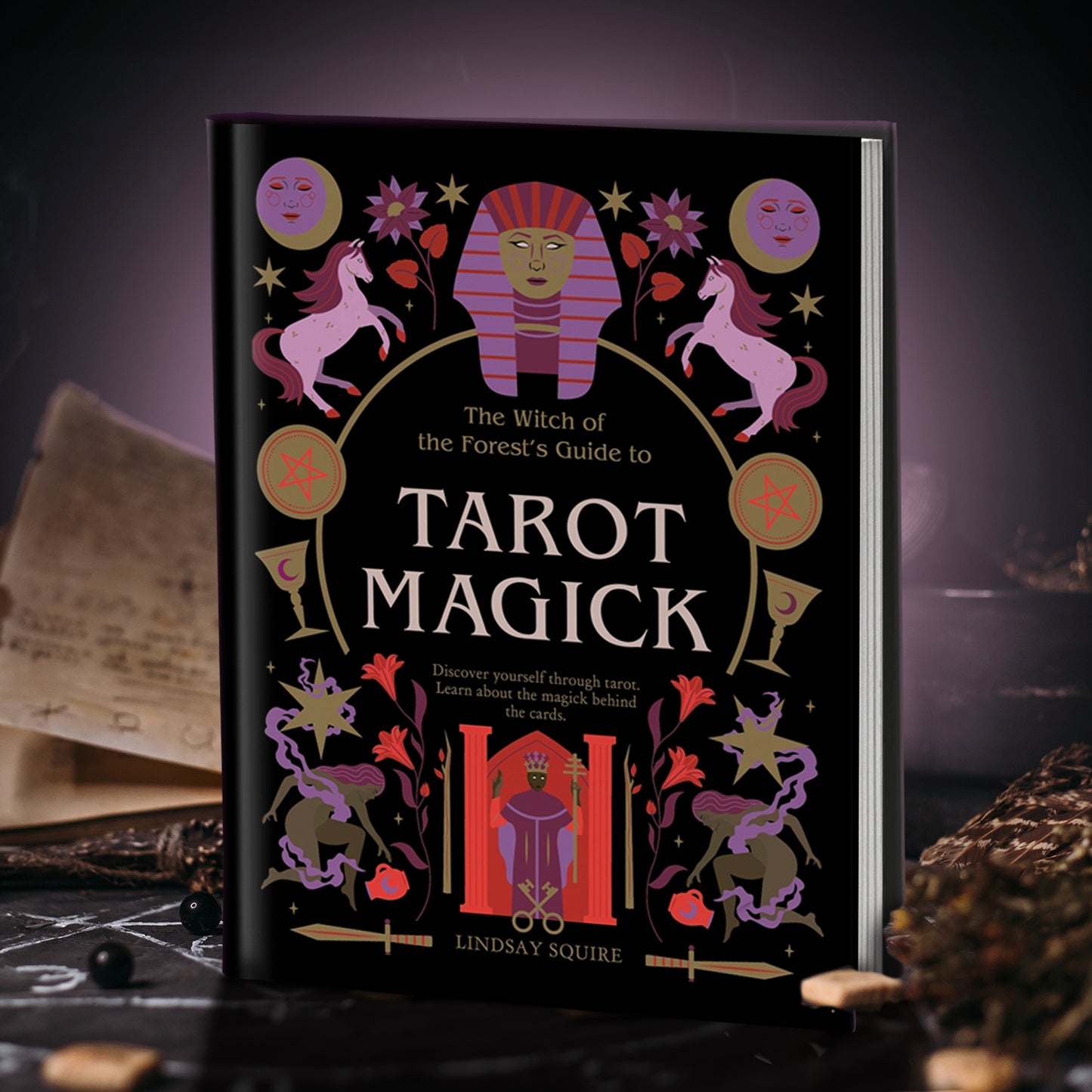 A hardcover copy of "The witch of the forest's guide to tarot magick: Discover yourself through tarot, learn about the magick behind the cards". The cover is black with bronze and magenta details.