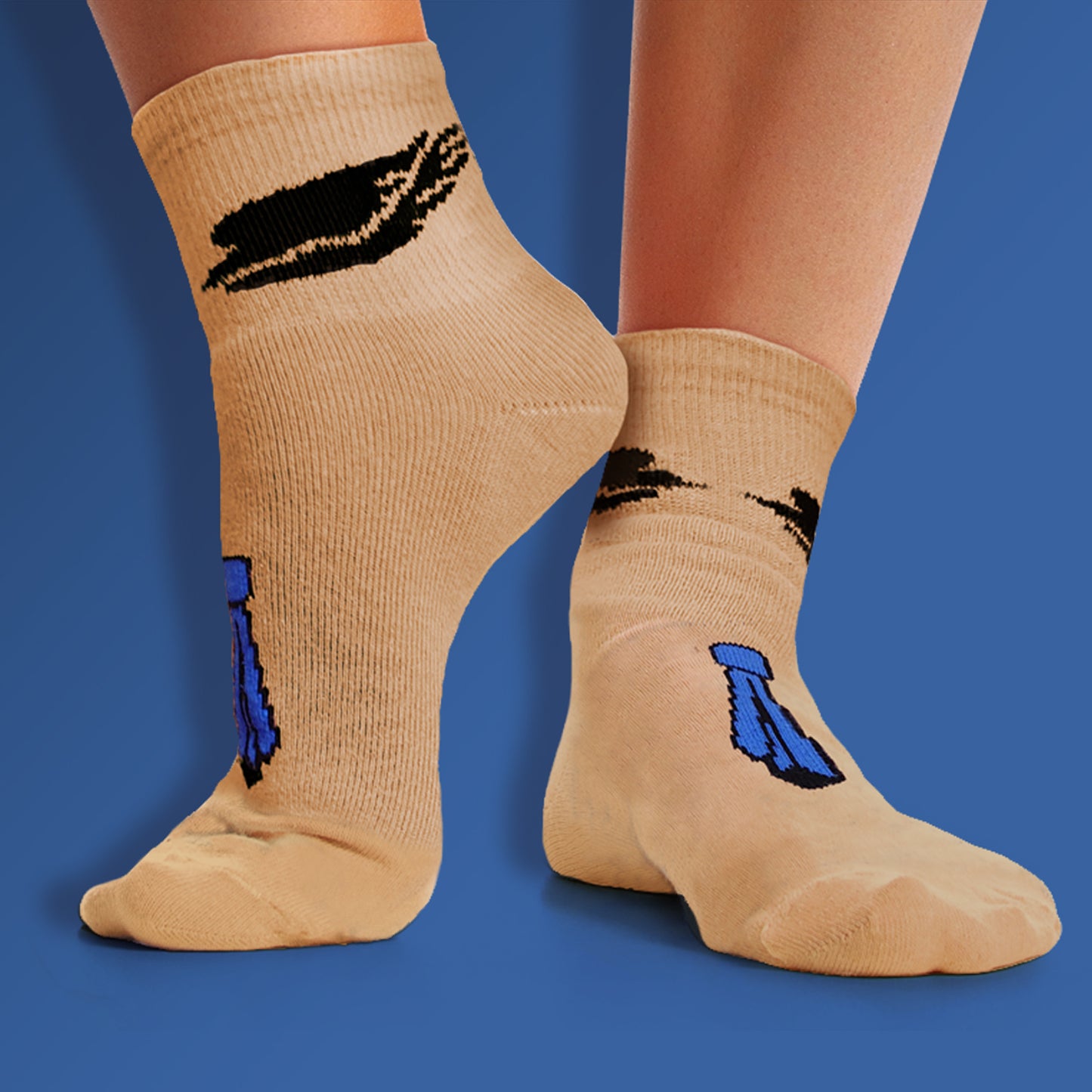 A model's feet wearing beige socks. The ankle of each sock has black angel wings. The front of each sock has a blue necktie, inside out.