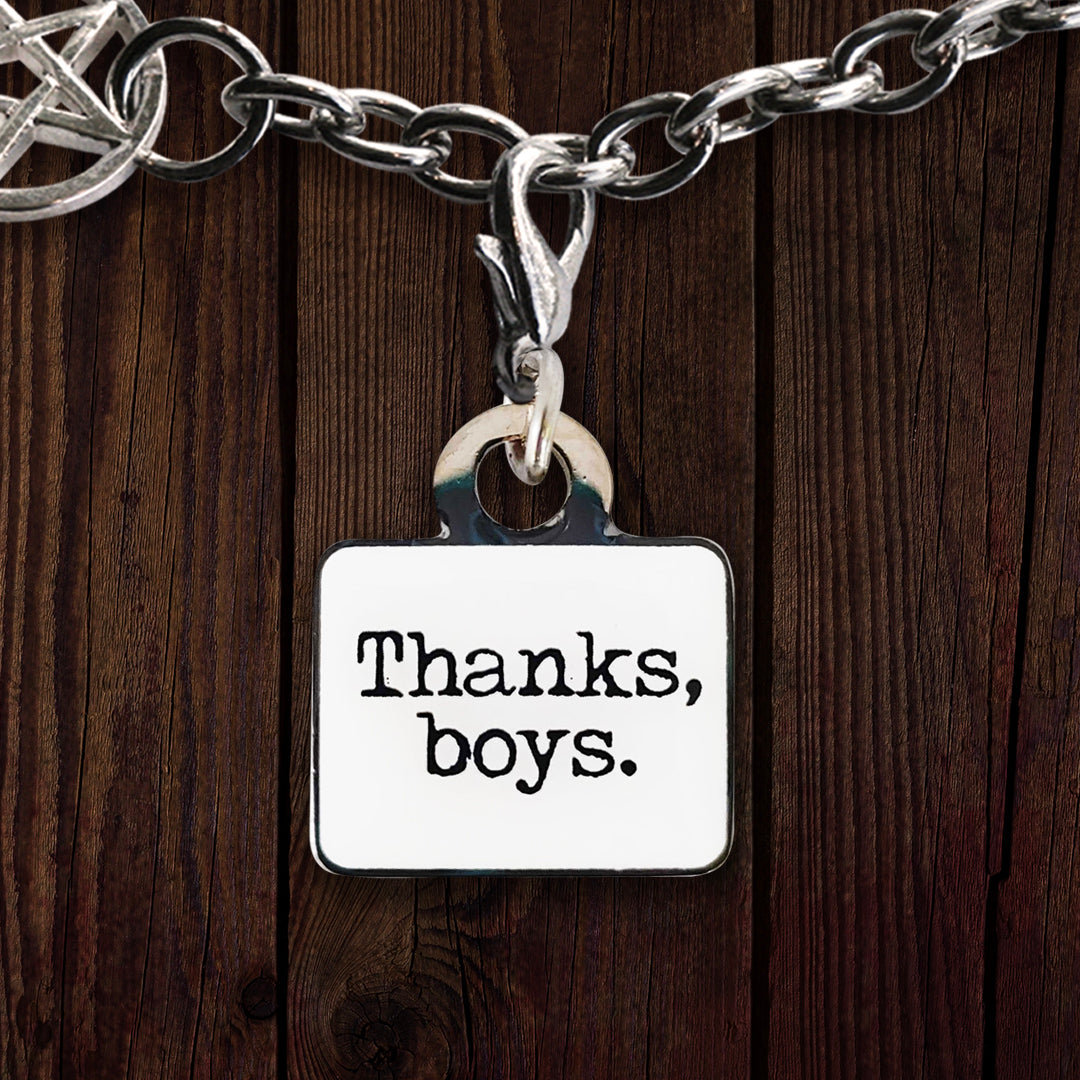 A silver-backed rectangular bracelet charm. The front is white and reads "Thanks, boys." in a typewriter-esque black font.