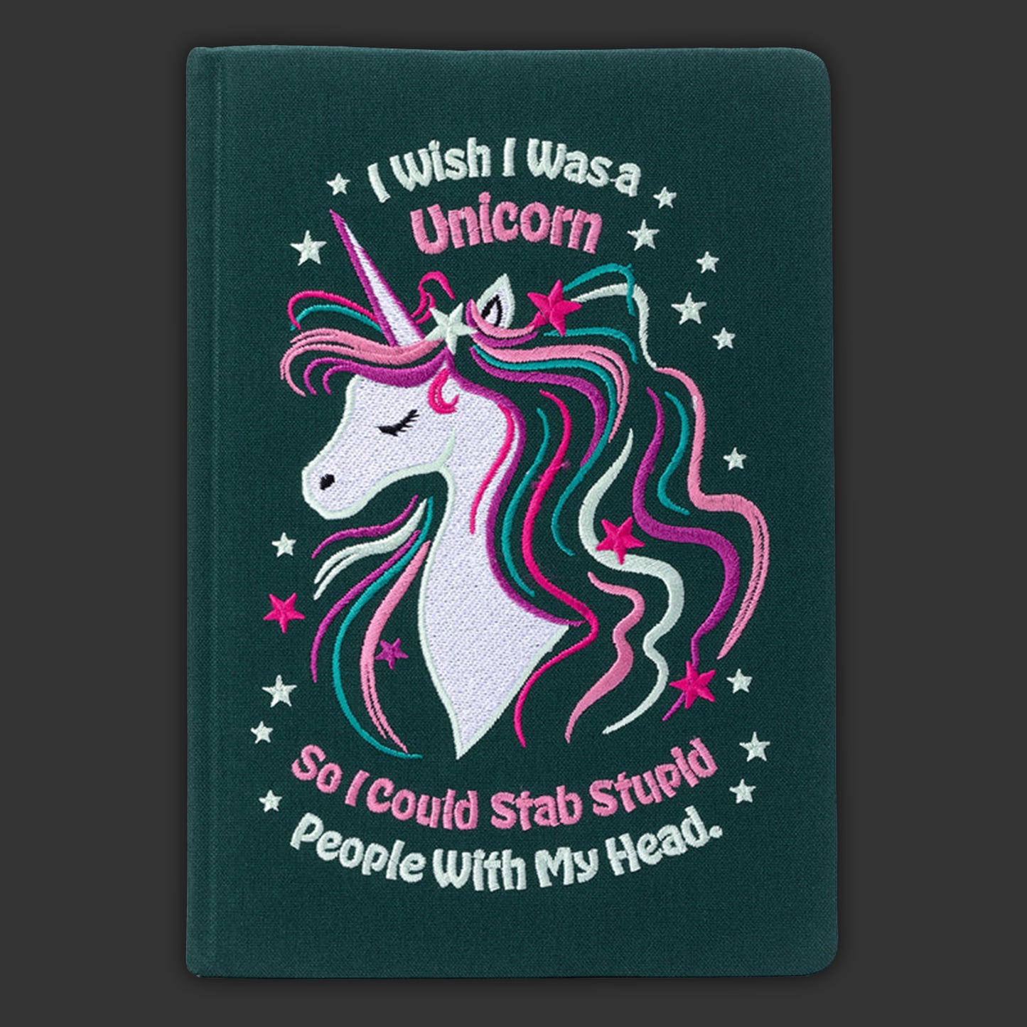 Notebook with unicorn illustration and humorous text on a dark green background