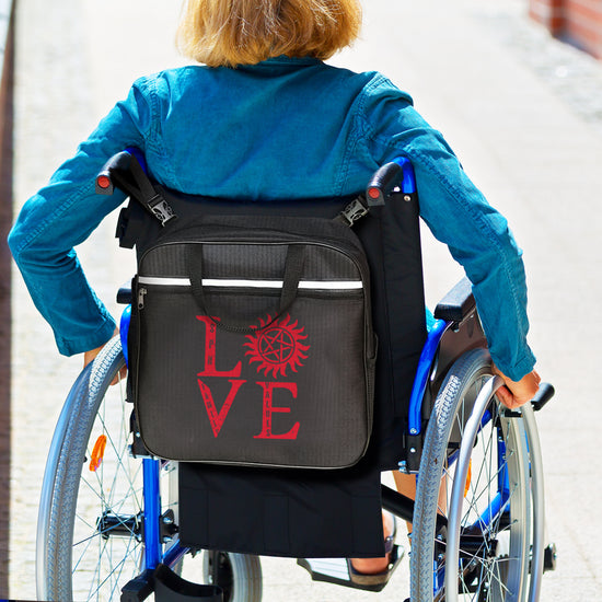 An image of a model in a wheelchair, rolling through a brick-lined ramp. On the back of the wheelchair is a black caddy bag, with red letters that spell out "LOVE." The "O" is replaced by the anti-possession symbol.