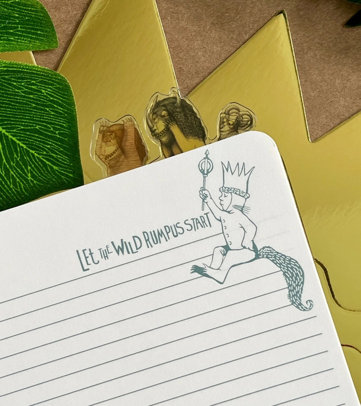 A page from the book with blank lines. In the top corner is a drawing of Max carrying a scepter. Green text says "let the wild rumpus start."