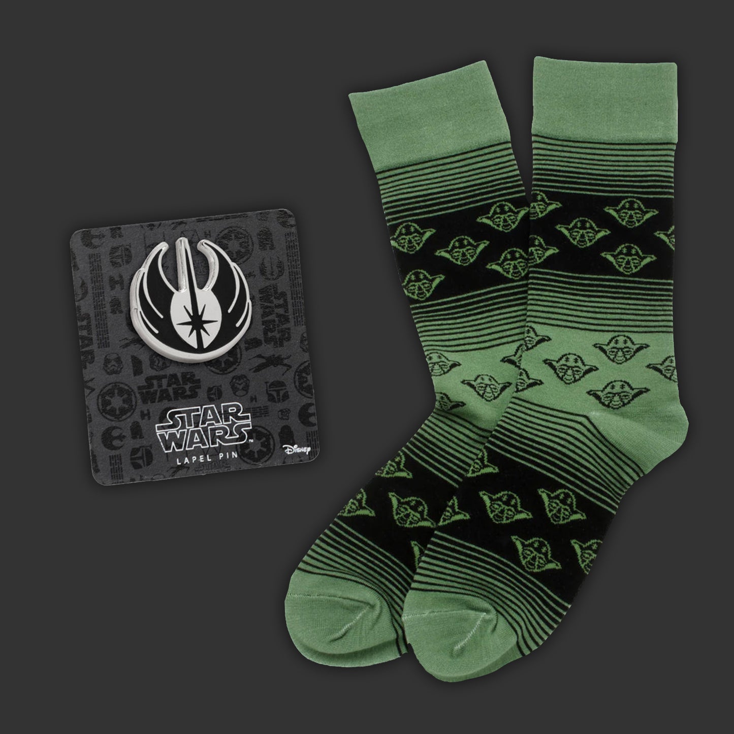 Green socks with Yoda pattern and Star Wars lapel pin on dark background