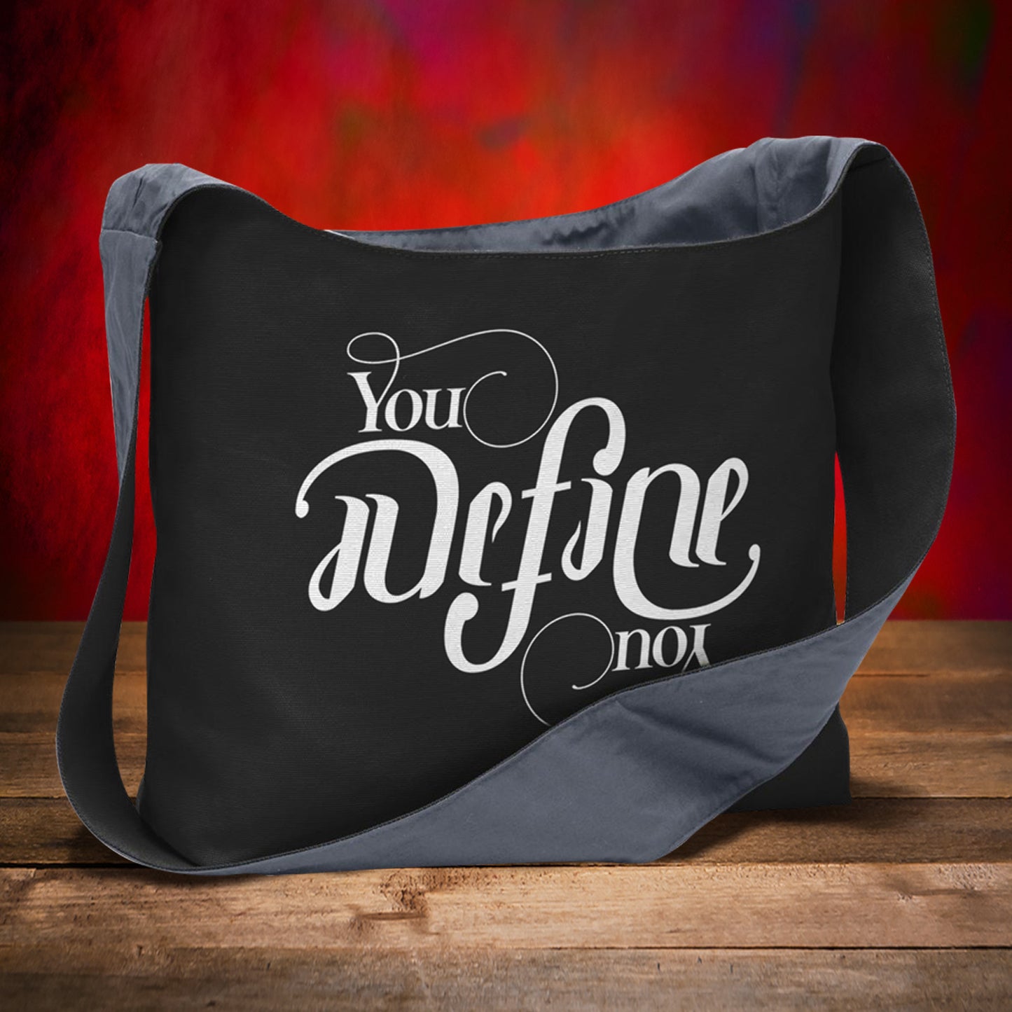 Black and gray bag with motivational quote on a wooden surface and red background