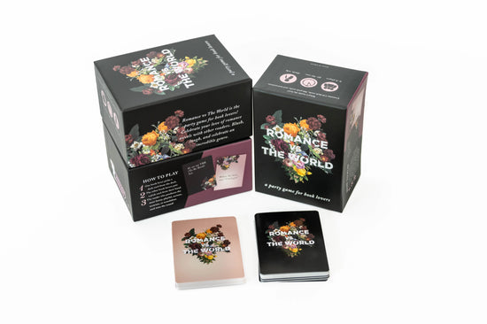 Black boxes on a white background. On the box covers are bouquets of flowers, with white text in the center saying "romance vs the world." A stack of black cards sits in front of the boxes.