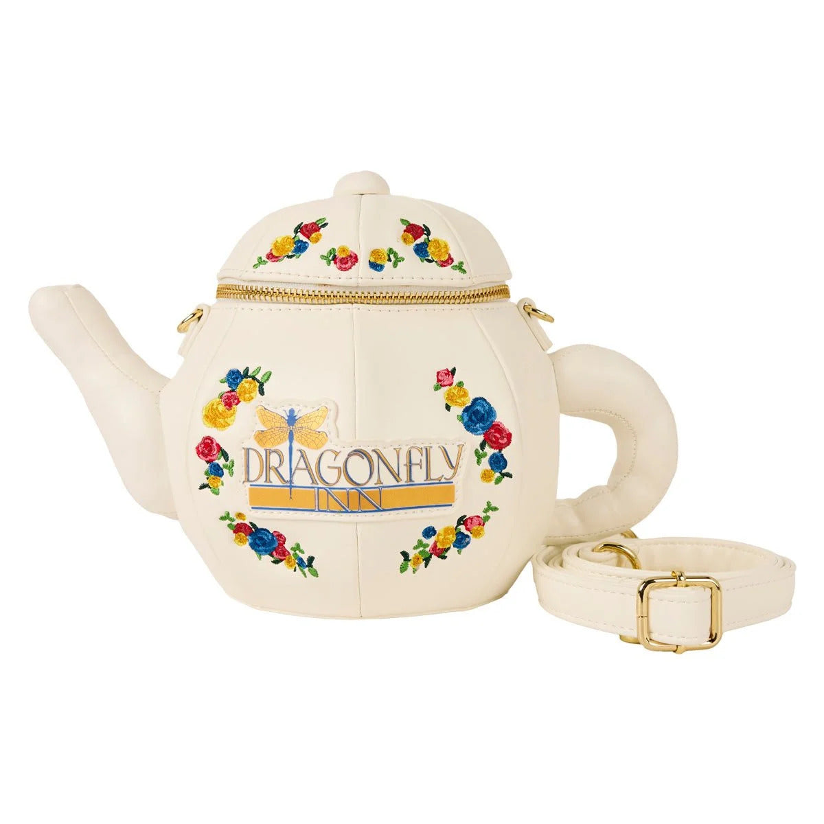 A white purse against a white background. The purse is shaped like a teapot. Around the front are colorful flowers. Gold and blue text says "Dragonfly Inn," with a gold and blue dragonfly next to it. The top of the teapot has a brass zipper. Next to the purse is a white strap, and a gold chain is attached to the front.