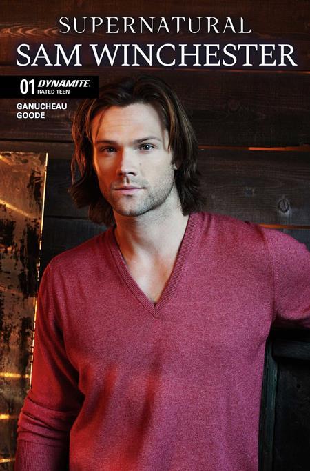 Sam Winchester comic book cover from Dynamite, featuring the character in a heathered maroon V-neck sweater against a dark wood-paneled background.